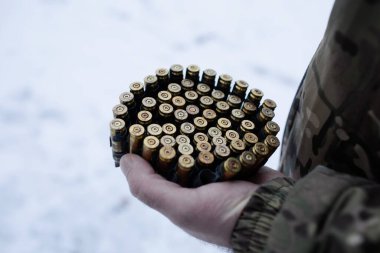 Askeri üniformalı bir adam elinde makineli tüfek kovanlarıyla makineli tüfek kemeri tutuyor. askeri çatışma.