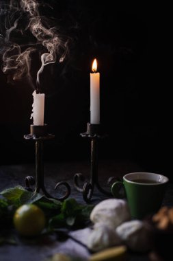 Kaynayan bir mumun dumanı. Şekerleme ve çay masada.