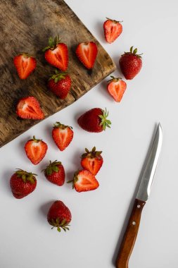 Olgun çilekler hafif bir zemin ve ahşap tahta üzerine saçılmış.