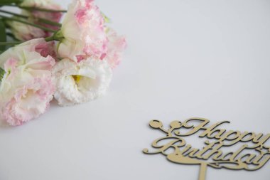 Beyaz arka plan, bir tarafında bir buket çiçek diğer tarafında da doğum günü olan bir kelime. Metin için yer