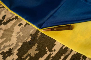 the cartridge lies on a yellow blue, Ukrainian flag and a khaki background. Military Pixel clipart