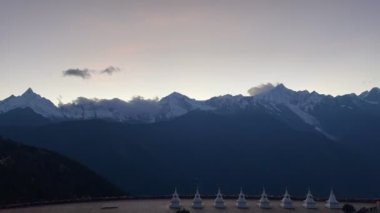 Çin 'in yunnan şehrinde, alacakaranlıkta Meili kar dağlarının eteklerinde beyaz pagoda' larda yürüyen yalnız bir Çinli kadının videosu.