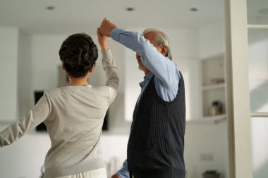 loving romantic senior asian couple dancing in living room at home