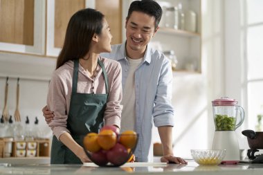 loving young asian couple chatting talking conversing in kitchen at home while preparing food