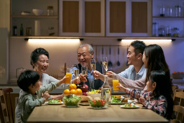 three generation asian family gathering at home celebrating holiday having a toast