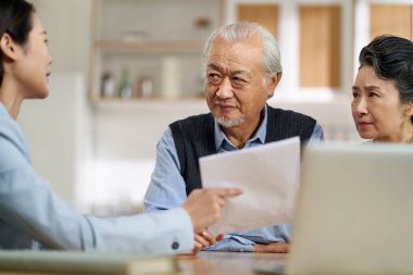 senior asian couple appears confused by and suspicious at a sales person selling financial product