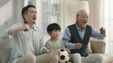 asian son father and grandfather watching live broadcasting of football match on TV together at home and disappointed by their team's performance