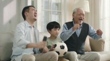 asian son father and grandfather watching live broadcasting of football match on TV together at home and disappointed by their team's performance