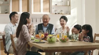 Mutlu üç Asyalı aile evde yemek yerken selfie çekiyor.