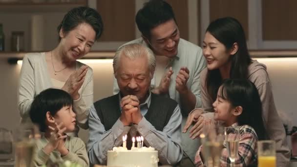 ケーキやろうそくの明かりでおじいちゃんの誕生日を祝う3世代のアジアの家族 — ストック動画