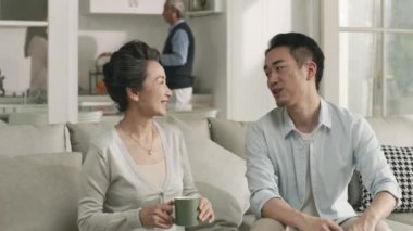 young asian adult son having a pleasant conversation with senior mother at home