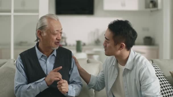 Asian Adult Son Sitting Couch Home Conversing Senior Father Happy — Video