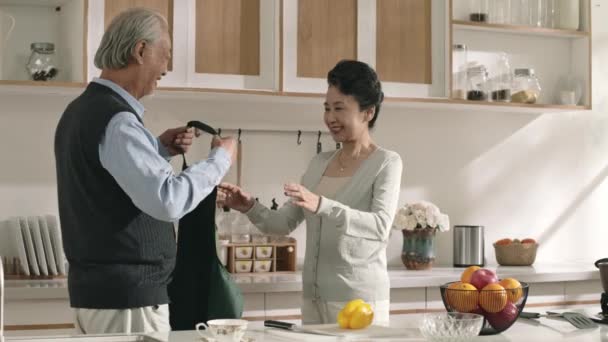 Suami Senior Yang Mencintai Asia Mengikat Celemek Untuk Istri Dapur — Stok Video