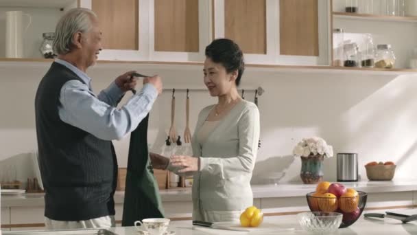 Opiekuńczy Starszy Azji Mąż Zakładanie Fartuch Dla Żony Kuchni Domu — Wideo stockowe