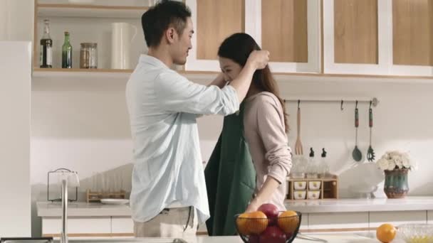 Opiekuńczy Młody Azji Mąż Zakładanie Fartuch Dla Żony Kuchni Domu — Wideo stockowe