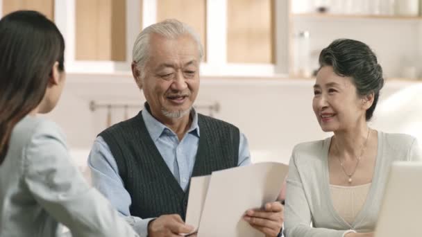 アジア系高齢者の夫婦は女性が提示する契約の条件に満足しています — ストック動画