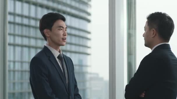 Dua Pengusaha Asia Berdiri Dan Mengobrol Dekat Jendela Kantor Modern — Stok Video