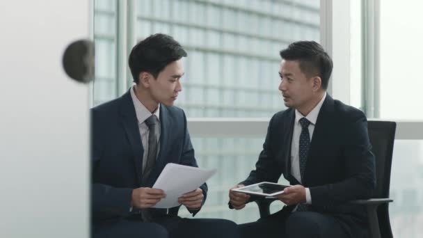 Two Asian Businesspeople Sitting Window Discussing Business Using Digital Tablet — Stock Video