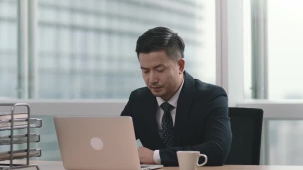Asiatischer Geschäftsmann Sitzt Modernen Büro Schreibtisch Und Blickt Auf Den — Stockvideo