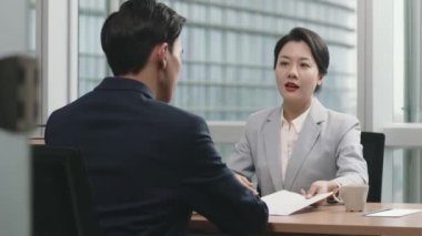 Genç Asyalı iş kadını yönetici erkek astıyla performans değerlendirmesi yapıyor.