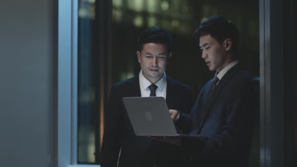 Två Asiatiska Affärsmän Står Vid Fönstret Kontoret Natten Har Diskussion — Stockvideo