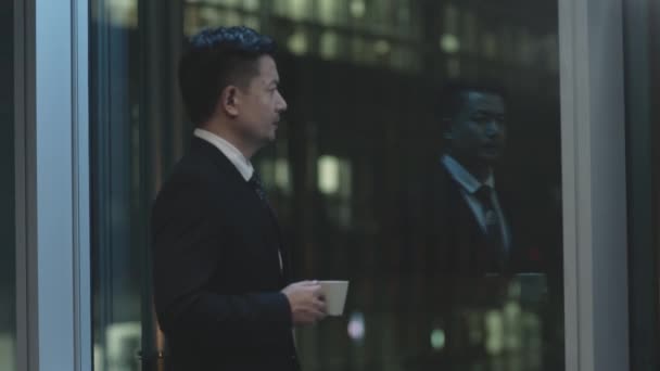 Азиатский Бизнесмен Работает Допоздна Стоя Глядя Окно Офисе Ночью — стоковое видео