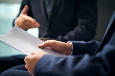 İki Asyalı iş adamının koltuklarda oturup ofiste iş tartışırken yakın plan çekimleri.