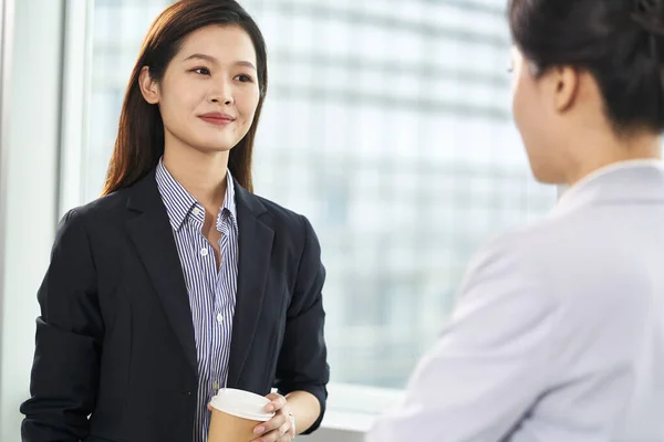 Two Young Asian Business Women Standing Chatting Window Modern Office — Stock Photo, Image