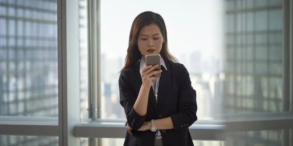 Jeune Asiatique Entreprise Femme Debout Par Fenêtre Regardant Téléphone Portable — Photo
