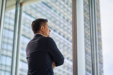 Asyalı iş adamının dikiz aynasından şehir manzarası kollarının çaprazlanmasına bakıyor.