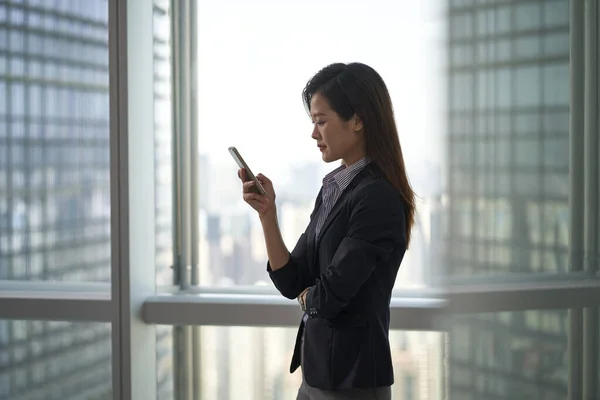 Jeune Asiatique Entreprise Femme Debout Par Fenêtre Regardant Téléphone Portable — Photo