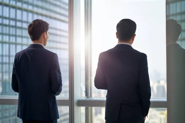 Zadní Pohled Dva Asijské Obchodní Muži Stojící Okna Kanceláři Při — Stock fotografie