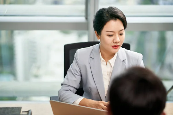 在现代办公室里 年轻的亚洲女企业家坐在办公桌前与男同事交谈 — 图库照片#