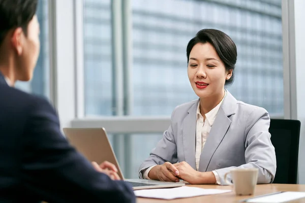 在现代办公室里 年轻的亚洲女企业家坐在办公桌前与男同事交谈 — 图库照片