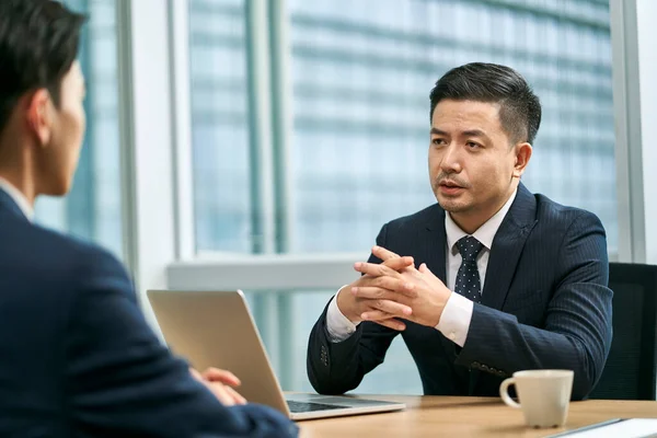 Два Азиатских Бизнесмена Сидящих Столом Лицом Лицу Современном Офисе Обсуждающих — стоковое фото