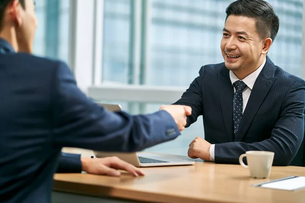 現代のオフィスで握手を交わすアジア系のビジネスマン2人 — ストック写真