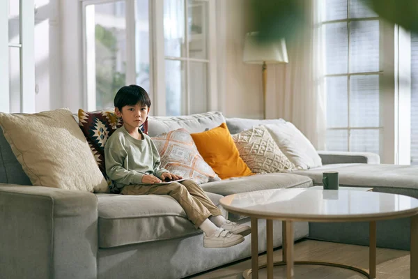 Маленький Азіатський Хлопчик Сидить Сімейному Дивані Вітальні Вдома Дивлячись Сумно — стокове фото