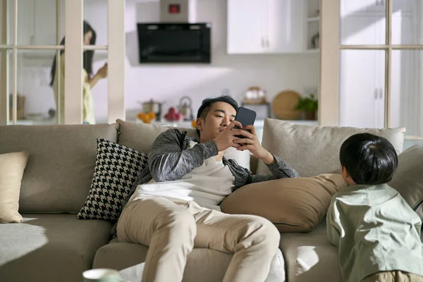 若いアジア系の夫婦は子供を無視してスマートフォンに依存していますスマートフォンやソーシャルメディアの中毒の概念 — ストック写真