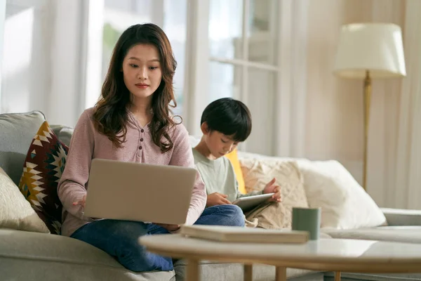 Joven Asiático Madre Sentado Sofá Trabajo Usando Portátil Ordenador Mientras —  Fotos de Stock