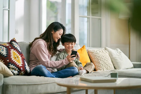 Feliz Asiático Madre Hijo Sentado Familia Sofá Mirando Teléfono Celular —  Fotos de Stock