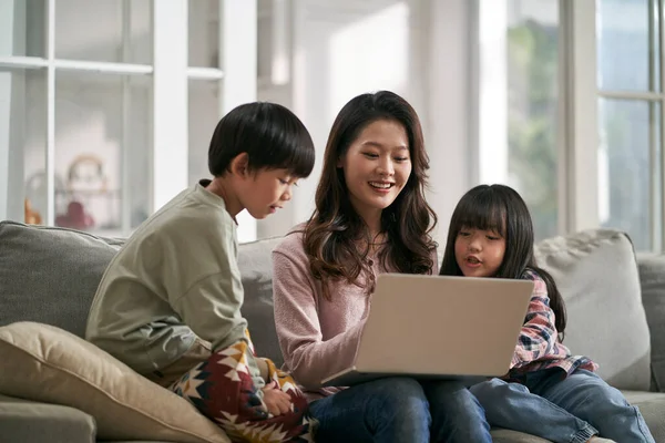 Happy young Chinese family using digital gadgets at home Stock