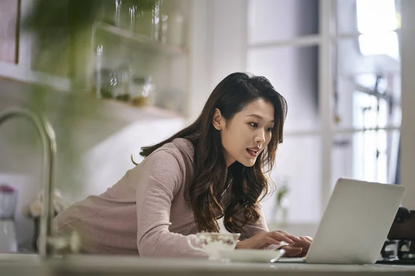 年轻的亚洲商人女自由职业者在家里用手提电脑在厨房工作 — 图库照片