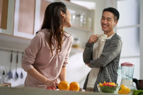 快乐的爱着一对年轻的亚洲夫妇 一边聊天 一边在家里厨房里一起做饭 — 图库照片
