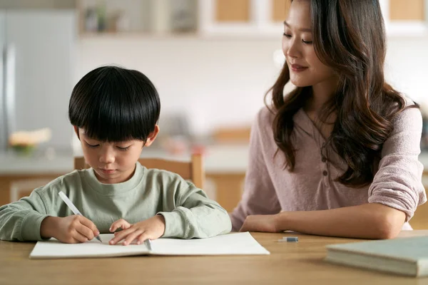 Mladá Asijská Matka Sedí Stolu Doma Pomáhá Syn Jeho Studie — Stock fotografie