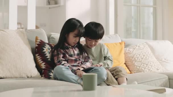 Twee Aziatische Kinderen Zitten Familie Bank Spelen Computer Spel Met — Stockvideo