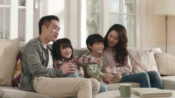 亚洲家庭有两个孩子坐在沙发上在家看电视 — 图库视频影像