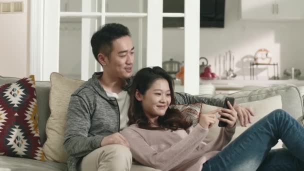 Mutlu Asyalı Genç Çift Koltukta Oturup Sohbet Ederken Cep Telefonu — Stok video