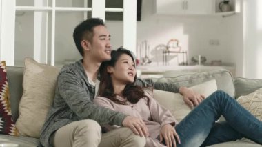 Genç Asyalı çift, aile koltuğunda oturup keyifli bir sohbet ediyorlar.