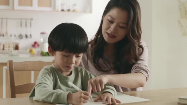 Young Asian Mother Sitting Dining Table Helping Son Homework Home — Stock Video
