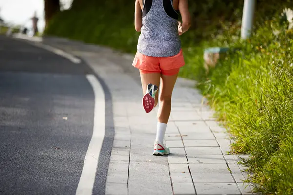 亚洲年轻女子慢跑者在城市公园户外运动的后视镜 免版税图库照片